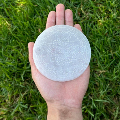 4 inch diameter round selenite charging plate with radiant heart flower design held in palm
