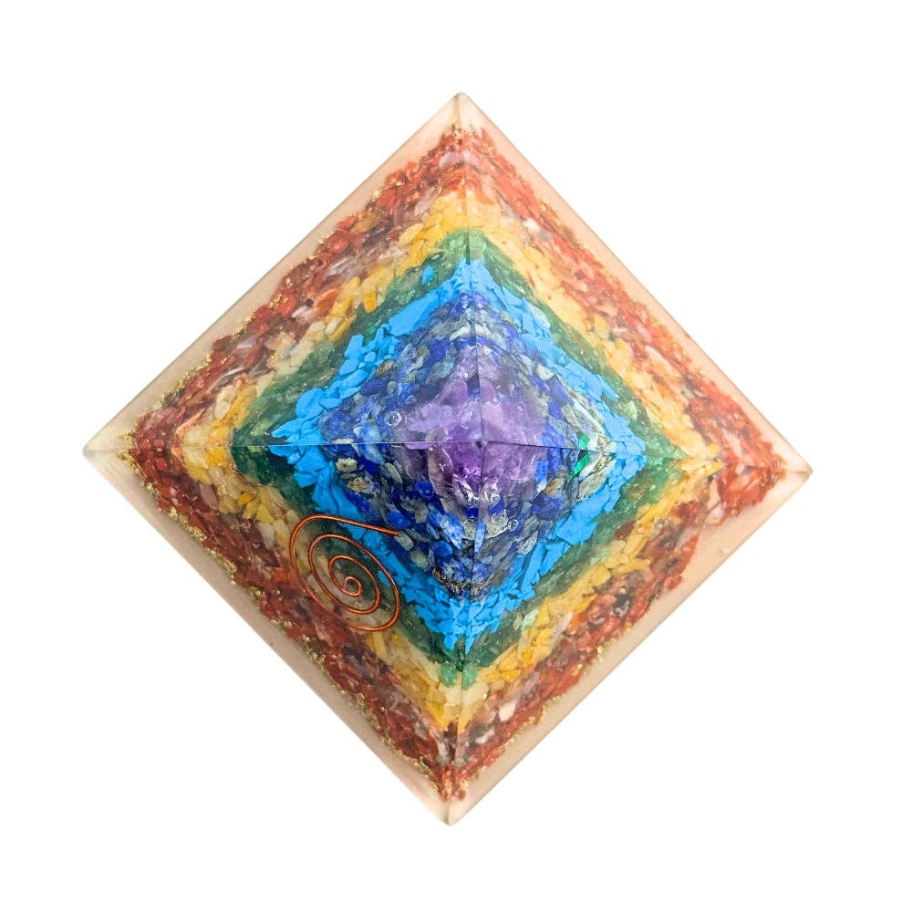 Multicolored organite chakra crystal pyramid with a copper spiral design on a white background
