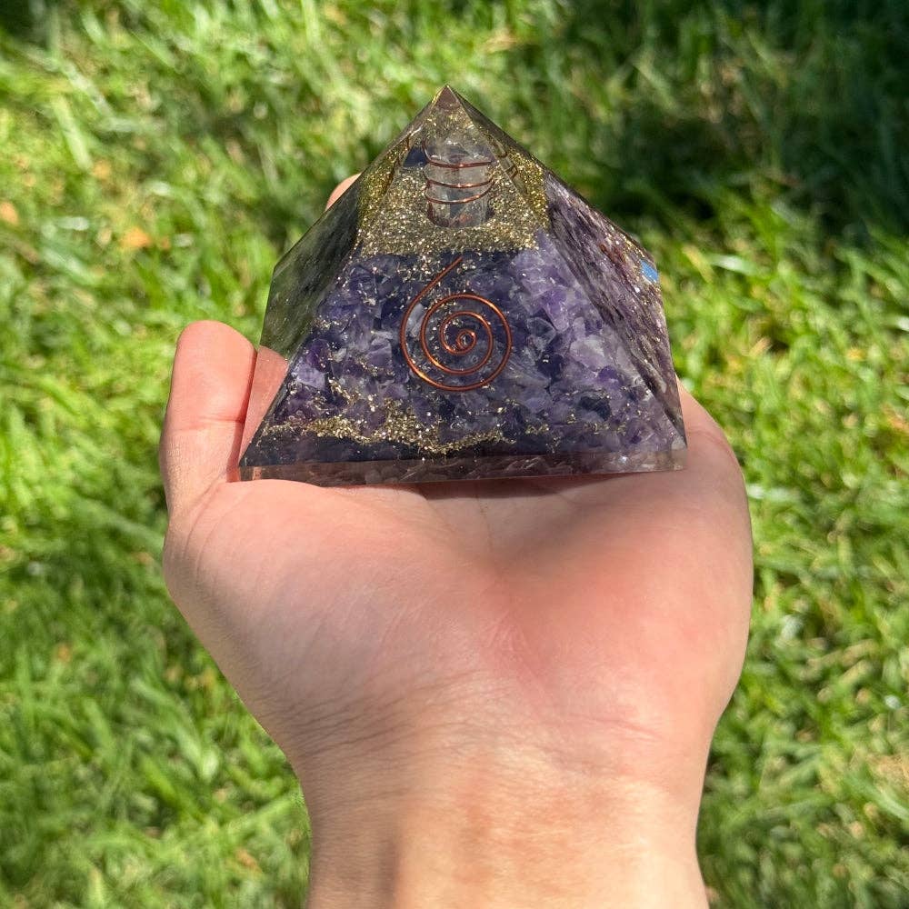 Hand holding Decorative pyramid with purple amethyst crystal, copper spiral, copper wrap quartz, and gold and copper shavings