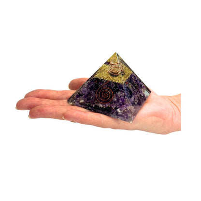 Decorative pyramid with purple amethyst crystal, copper spiral, copper wrap quartz, and gold and copper shavings held by hand